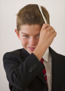Boy (10-11) in suit combing hair. Photo : Daniel Grill