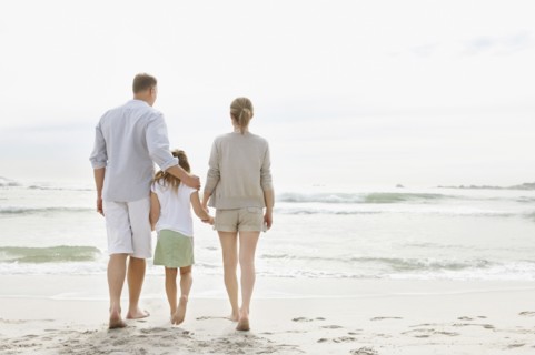 Girl (10-11) playing on beach with parents. Photo : Momentimages