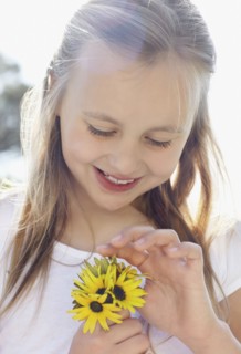 Girl (10-11) with sunflowers. Photo : Momentimages