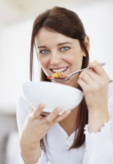 Portrait of mid adult woman eating from bowl. Photo : Momentimages