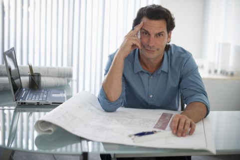 Architect with blueprints in office.