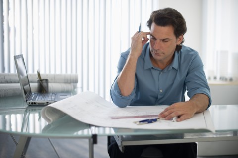 Architect with blueprints in office.