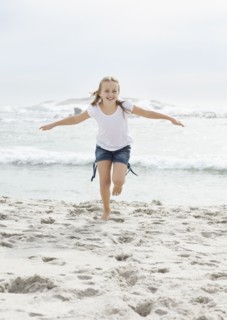 Portrait of girl (10-11) running on beach. Photo : Momentimages