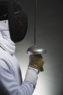 Studio portrait of fencer holding fencing foil.