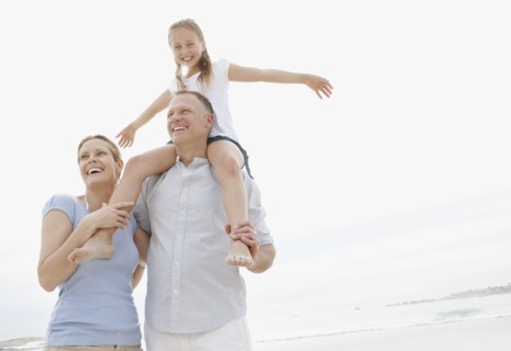 Girl (10-11) playing on beach with parents. Photo : Momentimages