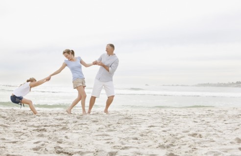 Girl (10-11) playing on beach with parents. Photo : Momentimages