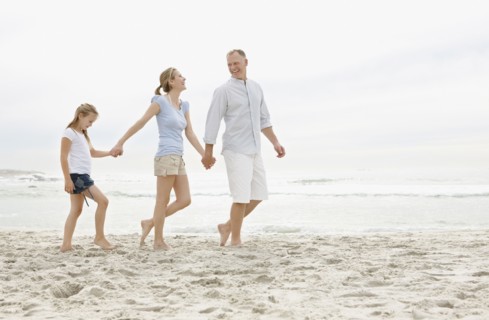 Girl (10-11) walking on beach with parents. Photo : Momentimages