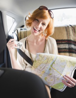 Portrait of young woman holding map in car. Photo : Jamie Grill