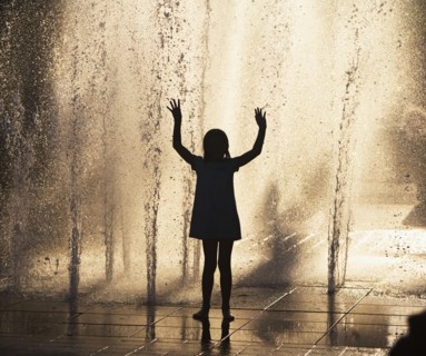 Silhouette of girl playing in fountain. Photo : fotog