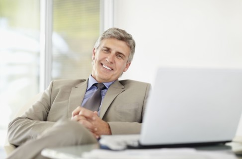 Portrait of cheerful businessman with laptop. Photo : Momentimages