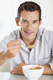Cheerful mid adult man eating cornflakes. Photo : Momentimages