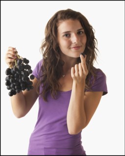 Young woman eating grapes. Photo : Mike Kemp
