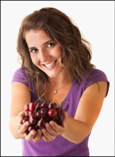 Young woman holding cherries. Photo : Mike Kemp