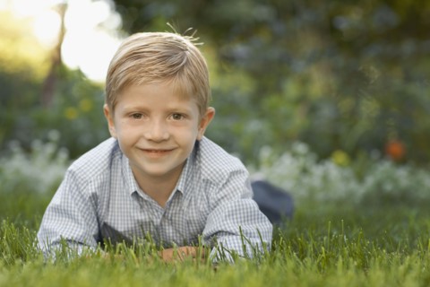 Portrait of boy (6-7) lying on grass. Photo : FBP