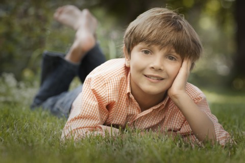 Portrait of boy (8-9) lying on grass. Photo : FBP