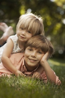 Portrait of brother and sister (2-8-9) lying on grass. Photo : FBP