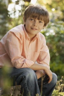 Portrait of boy (8-9) sitting in garden. Photo : FBP