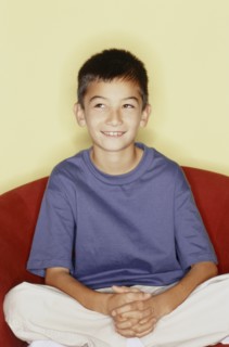 Cute young boy sitting in red chair. Photo : Fisher Litwin