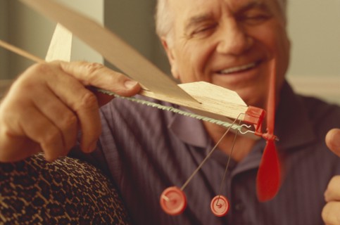 Senior man playing with toy airplane. Photo : Fisher Litwin