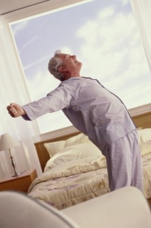 Senior man stretching in his bedroom. Photo : Fisher Litwin