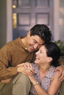 Happy couple sitting in front of their home. Photo : Fisher Litwin