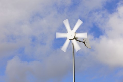 Old wind turbine against cloudy sky. Photo : Jon Boyes