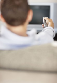Mid adult man in front of televisionchanging channels. Photo : Momentimages