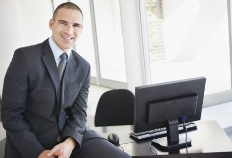 Businessman sitting on office desk. Photo : Momentimages