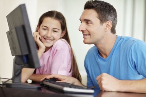 Father with daughter (10-11) playing with computer. Photo : Momentimages