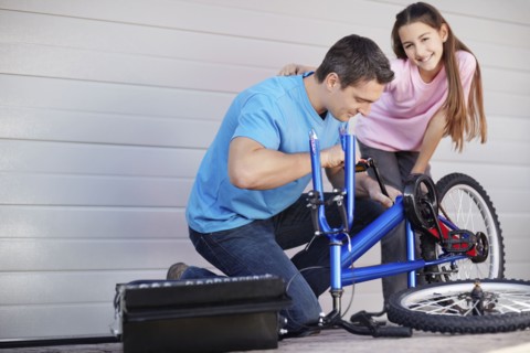 Father with daughter (10-11) fixing bike. Photo : Momentimages