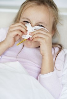 Girl (10-11) blowing nose with thermometer in mouth. Photo : Momentimages