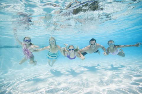 Family with three daughters (4-5,6-7,8-9) swimming underwater.