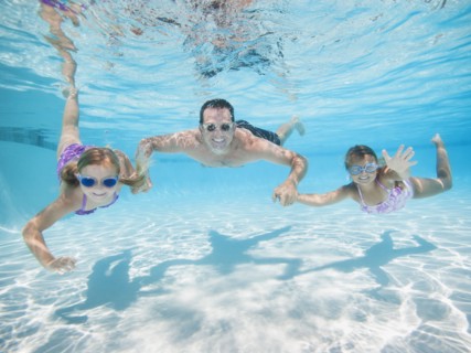 Father with two daughters (6-7,8-9) swimming underwater.