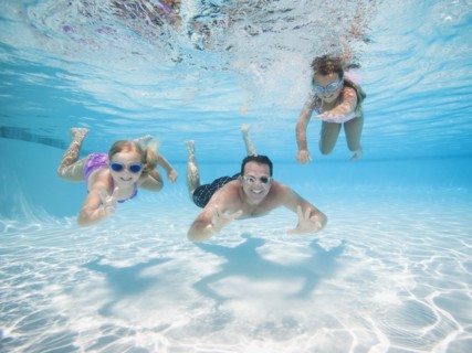 Father with two daughters (6-7,8-9) swimming underwater.