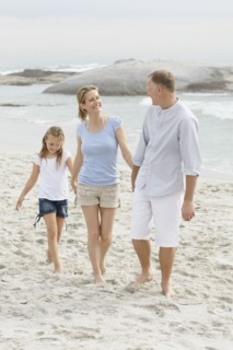 Girl (10-11) playing on beach with parents. Photo : Momentimages