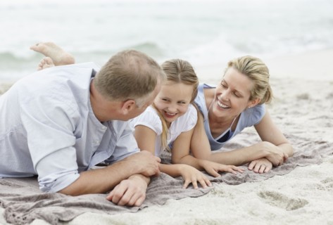 Girl (10-11) playing on beach with parents. Photo : Momentimages