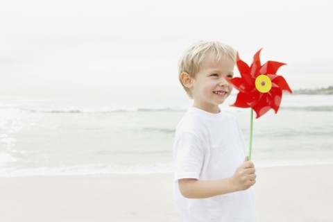 Boy (4-5) holding red pinwheel. Photo : Momentimages