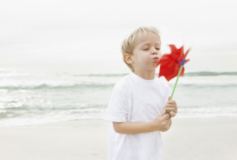 Boy (4-5) blowing on red pinwheel. Photo : Momentimages