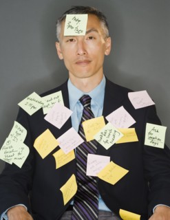 Businessman with post-it sticking on him, studio shot. Photo : Jamie Grill