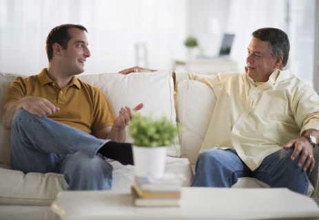 USA, New Jersey, Jersey City, Father and son talking on sofa in living room.