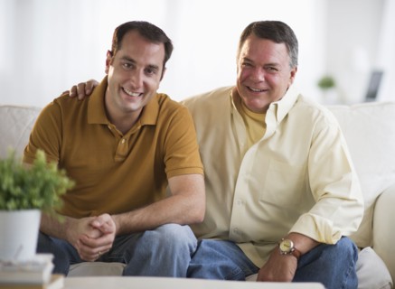 USA, New Jersey, Jersey City, Portrait of father and son sitting on sofa in living room.