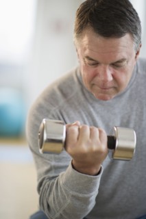 USA, New Jersey, Jersey City, Fitness instructor assisting man using hand weight in gym.