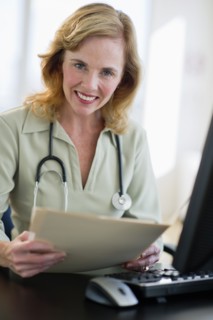 USA, New Jersey, Jersey City, Portrait of female doctor holding medical record in office.