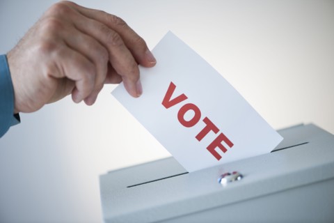 Man putting vote card into box.