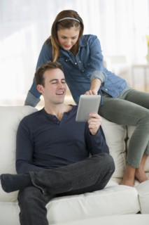USA, New Jersey, Jersey City, Portrait of young couple sitting on sofa with digital tablet.
