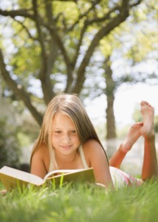 USA, New York, Girl (10-11) reading book in park. Photo : Jamie Grill Photography
