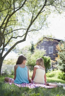 USA, New York, Two girls (10-11, 10-11) sitting on blanket in backyard. Photo : Jamie Grill