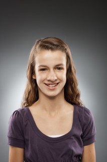 Portrait of girl (12-13) looking at camera and smiling, studio shot. Photo : FBP