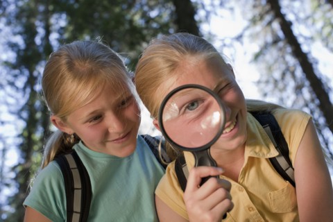Canada, British Columbia, Fernie, sisters looking through magnifying glass. Photo : Dan Bannister