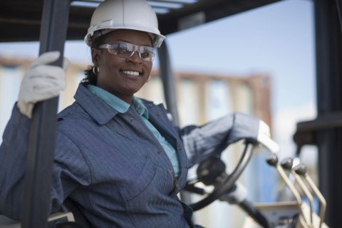 Portrait of female construction worker driving mechanical digger. Photo : Dan Bannister